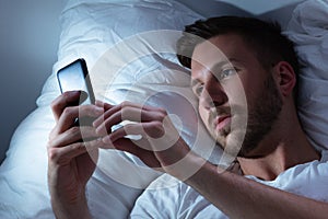 Man Using Cellphone In Bed