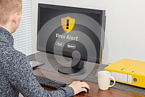 Man using computer with computer virus alert photo