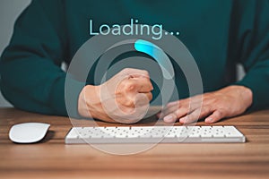 Man using a computer keyboard to download and waiting to loading digital business data form website.