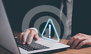 Man using computer laptop with triangle caution warning sign for notification error. Computer virus detected, personal data