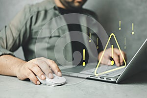Man using computer laptop with triangle caution warning sign for notification error