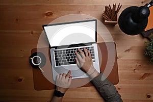 Man using computer laptop on wooden table in dark room.