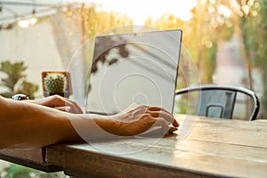 Man using computer mouse working with laptop on table in morning.