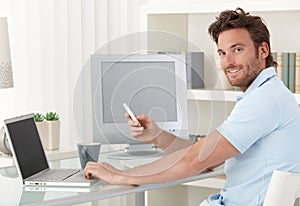 Man using computer and phone at home