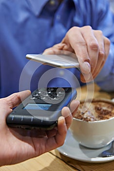 Man Using Contactless Payment App On Mobile Phone In Cafe