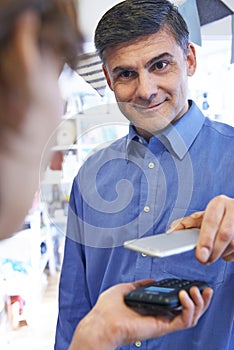 Man Using Contactless Payment App On Mobile Phone In Store