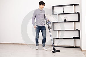 Man using cordless vacuum cleaner to clean laminate flooring