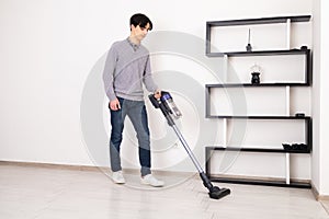 Man using cordless vacuum cleaner to clean laminate flooring