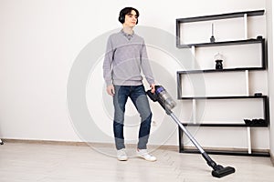 Man using cordless vacuum cleaner to clean laminate flooring