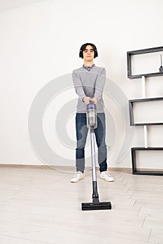 Man using cordless vacuum cleaner to clean laminate flooring