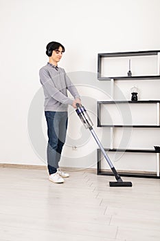 Man using cordless vacuum cleaner to clean laminate flooring