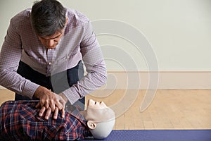 Man Using CPR Technique On Dummy In First Aid Class