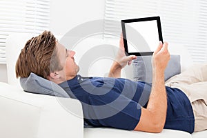 Man Using Digital Tablet With Blank Screen On Sofa