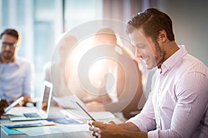 Man using digital tablet while coworker interacting in the background