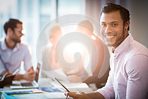 Man using digital tablet while coworker interacting in the background
