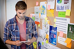 Man using digital tablet next to the board with sticky notes