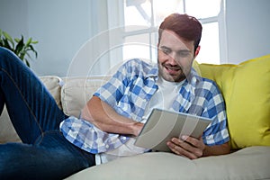 Man using digital tablet while relaxing on sofa