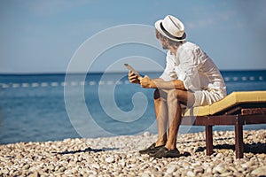 Man using digital tablet at sea beach