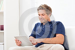 Man using digital tablet on sofa at home