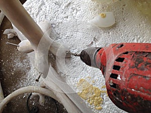 Man using an electric hand drill to drive a into resin scu