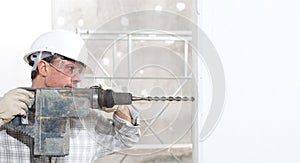 Man using an electric pneumatic drill making a hole in wall, professional construction worker with safety hard hat,, gloves and