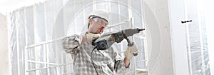 Man using an electric pneumatic drill making a hole in wall, professional construction worker with safety hard hat, hearing