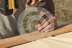 Man using electrical scredriver to attach construction elements.