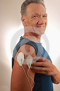 Man using an Electro Therapy Massager or Tens Unit on his Deltods