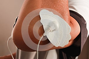 Man using an Electro Therapy Massager or Tens Unit on his elbow