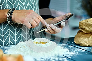 Man using electronic tablet pc in kitchen for baking. Man searching for food recipe in tablet computer.