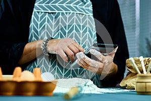 Man using electronic tablet pc in kitchen for baking. Man searching for food recipe in tablet computer.