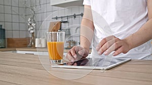 Man using electronic tablet pc in kitchen. Man searching food recipe in tablet computer. Close up man cook touching