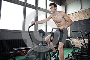 Man using exercise bike at the gym. Fitness male using air bike for cardio workout at Functional training gym