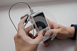 Man using finger pulse oximeter, healthcare monitoring concept. Pulse oximeter on a white background