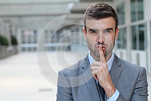 Man using a finger sign to request someone to remain silent