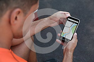 Man using fitness app on smartphone outdoors, closeup