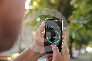 Man using fitness app on smartphone outdoors, closeup