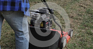 Man using gas powered aerating machine to aerate residential grass yard. Preparing the lawn for summer with an aerator in early