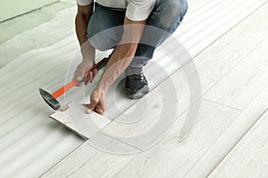 Man using hammer during installation of new laminate flooring, closeup