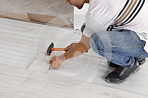 Man using hammer during installation of new laminate flooring, closeup