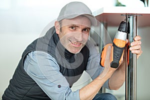 man using hand drill to assemble table