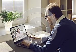 Man using his laptop, enjoying virtual visit to clinic and consulting online doctor