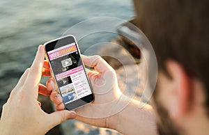 Man using his mobile phone on the coast to watch videos