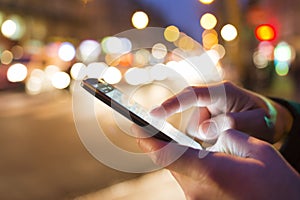 Man using his Mobile Phone in the street, night light bokeh