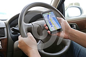 Man using his mobile phone to navigate with map application while driving. Dangerous driver. Concept and idea of safety driving photo