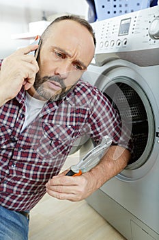 man using phone near washing machine
