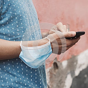 Man using his smartphone wearing a mask in his arm