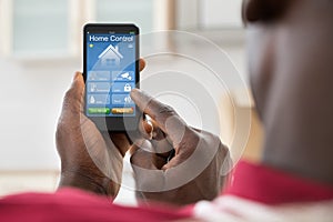 Man Using Home Control System On Mobilephone