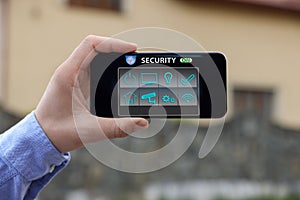 Man using home security application on smartphone in front of house outdoors, closeup