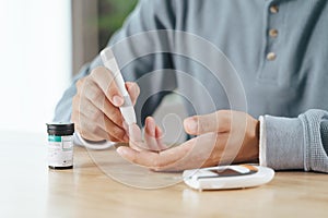 Man using lancet on finger for checking blood sugar level by Glucose meter, Healthcare and Medical, diabetes, glycemia concept